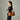 Side view of a woman wearing a brown leather shoulder bag with chain strap against a neutral background