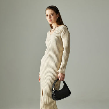 Woman in a ribbed knit dress holding a compact black Braun Büffel handbag in a minimalist studio setting